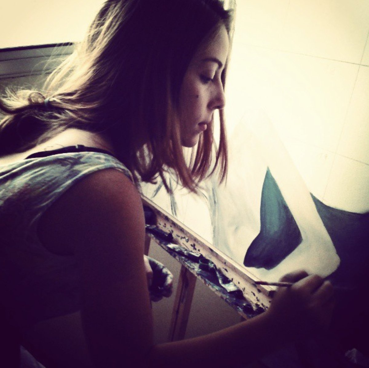Diana in profile, painting at the easel in soft window light.